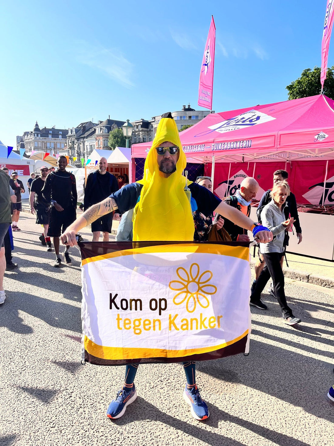 Ken Schepmans in bananenpak met de vlag van Kom op tegen Kanker